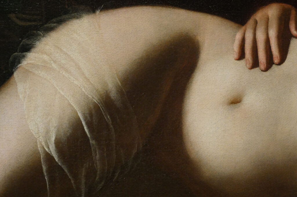 Photographie pour le portfolio d'un détail d'un tableau d'Artemisia Gentileschi sur lequel on voit une partie du corps d'une femme dénudée et allongée sur son flanc gauche. Sa main est posée sur sa hanche et un voilage s'enroule sur sa cuisse.