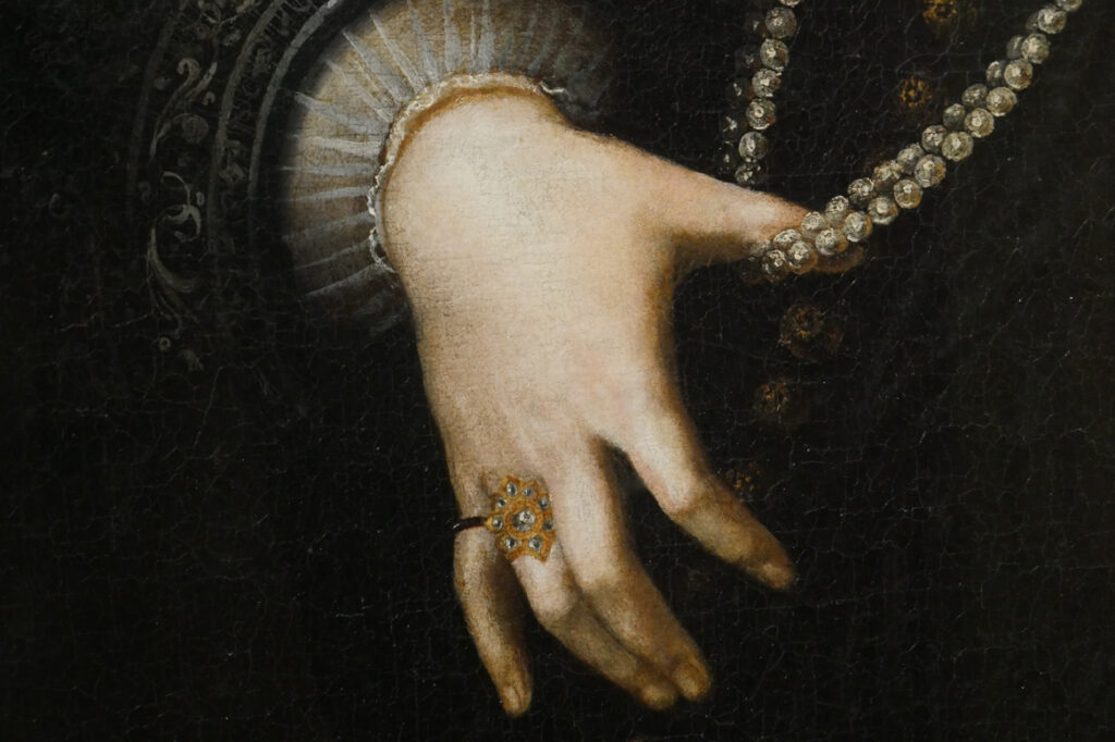 Photographie pour le portfolio d'un détail d'un tableau d'Artemisia Gentileschi sur lequel on voit une main qui tient un collier de perles.