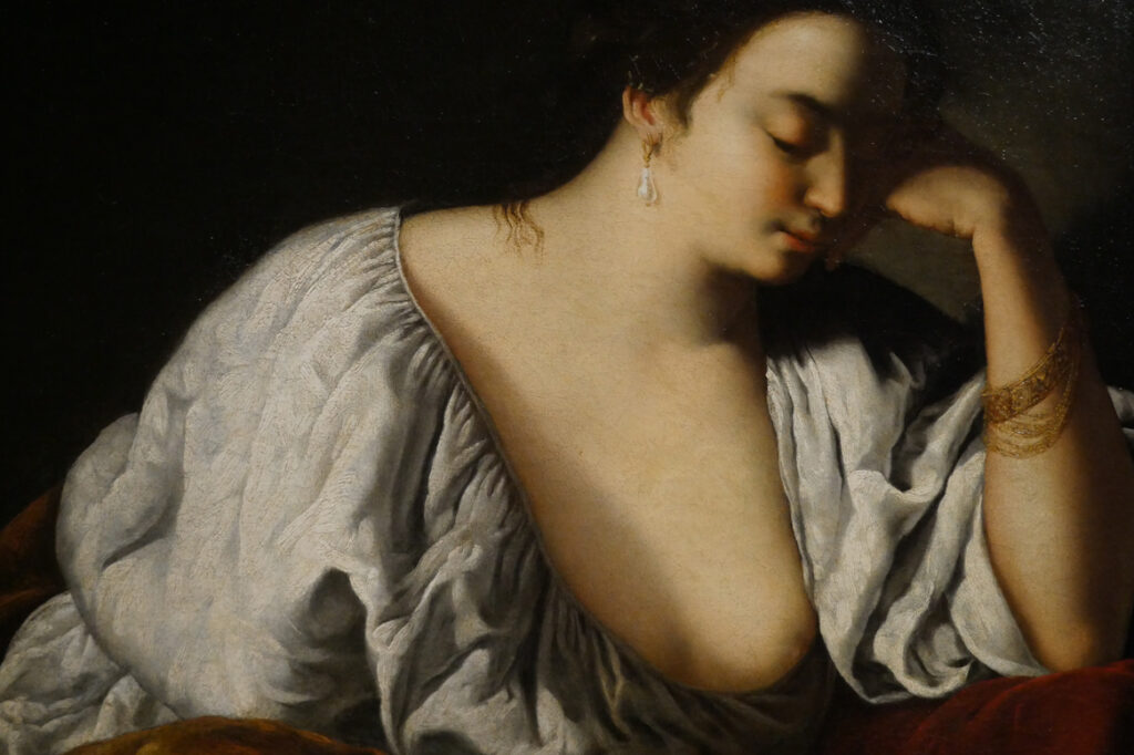 Photographie pour le portfolio d'un détail d'un tableau d'Artemisia Gentileschi sur lequel on voit la partie supérieure d'une femme au corsage blanc ouvert sur sa poitrine qui tient sa tête de sa main gauche.